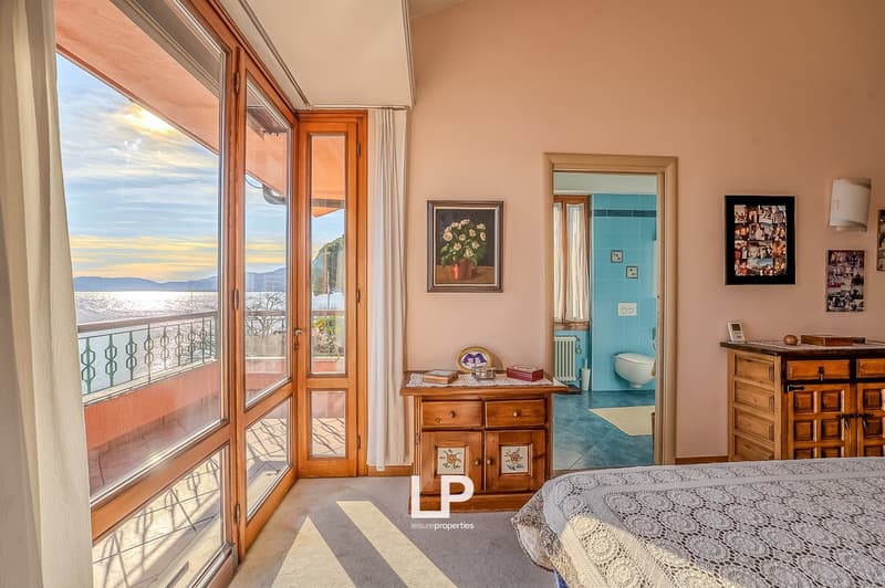 bedroom with balcony, large windows, wooden cabinet, bed, picture frames, bathroom with toilet and tiles