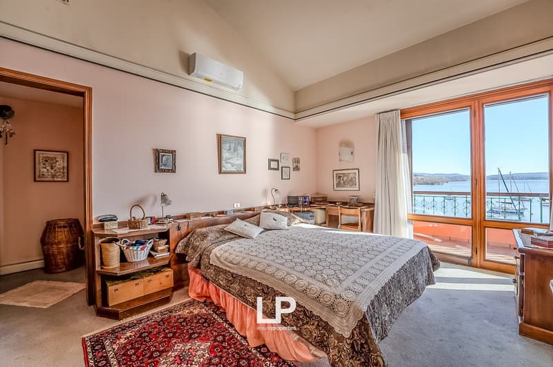Bedroom with bed, desk, chair, and balcony with lake view