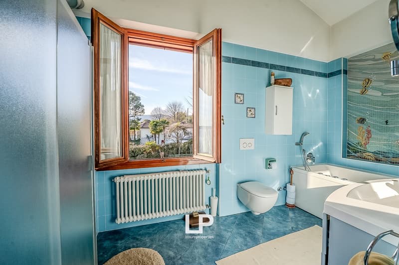 blue tiles, white fixtures, large window, bathtub, toilet, radiator, sink