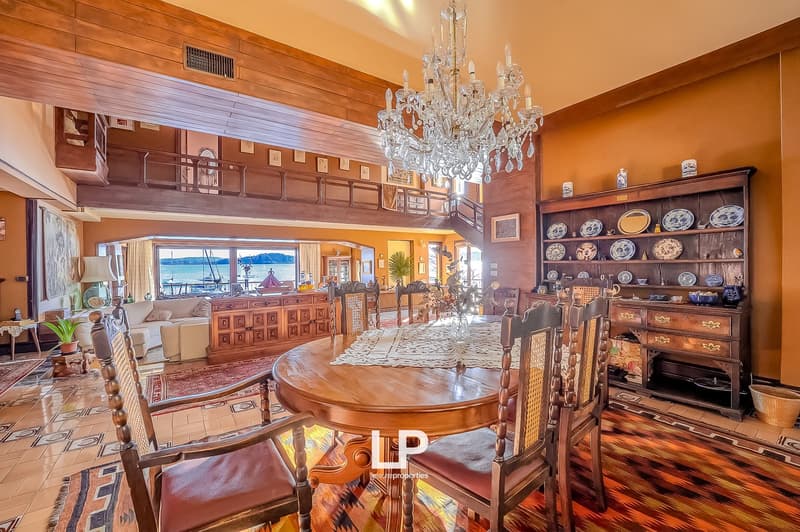 dining room with wooden table, chairs, chandelier, wooden cabinet, couch, and a view of the sea