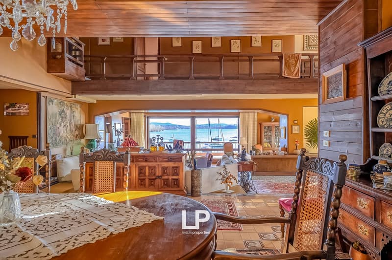 dining room with wooden table, chairs, chandelier, wooden cabinet, large windows with sea view
