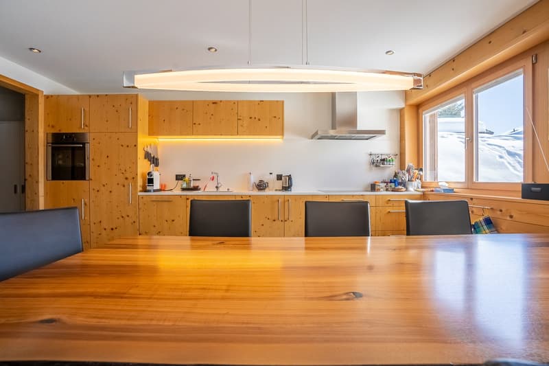 modern kitchen with wooden cabinets, large dining table, large windows, modern lighting