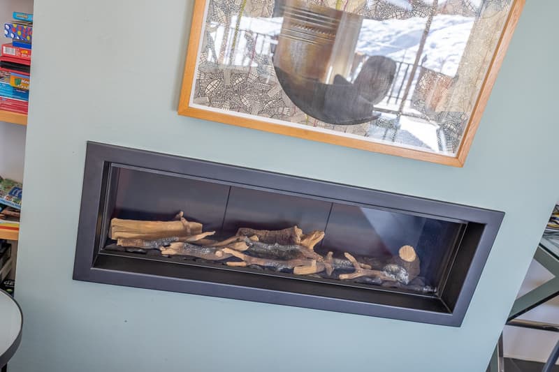 Fireplace with logs, mounted on wall, picture frame above