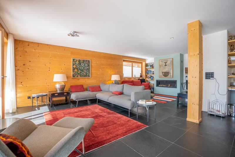 wooden wall, fireplace, gray sofa, red rug, wooden floor, lamps, side tables, shelves, books, paintings