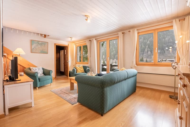 living room with sofa, armchairs, coffee table, rug, TV, wooden floor, wooden ceiling, large windows, wooden cabinet, wooden staircase