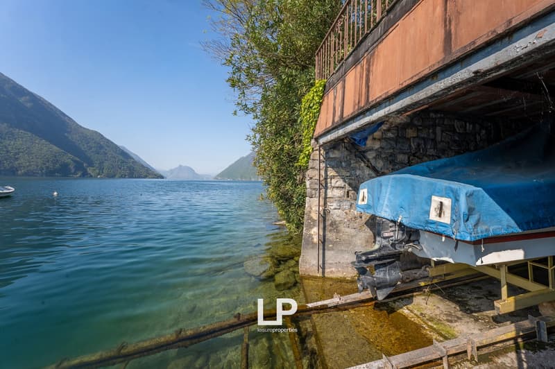 Lakefront property with a boat dock, stone wall, and a boat covered with a tarp