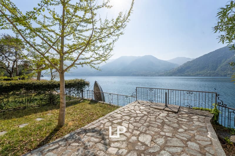 Stone pathway leading to a lake, metal railings, a tree, and a boat on the lake