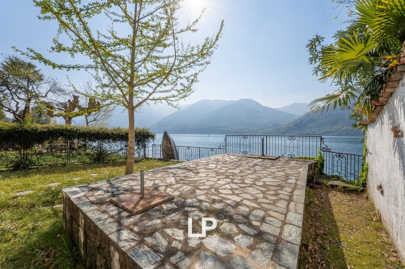 Stone patio, metal railing, lake view, greenery, mountains in the background