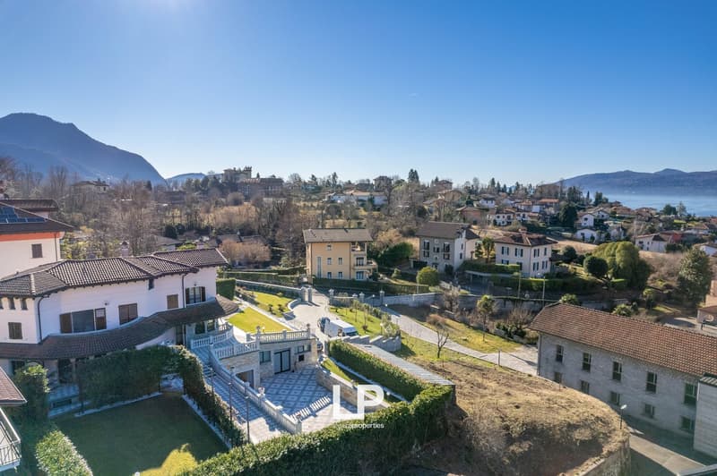 Villa with large garden, driveway, solar panels, surrounded by other houses, mountains in the background
