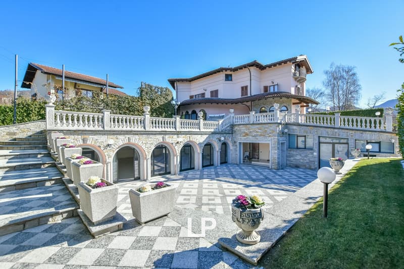 elegant building with arched doors and steps, stone and brick exterior, patio, several flower vases