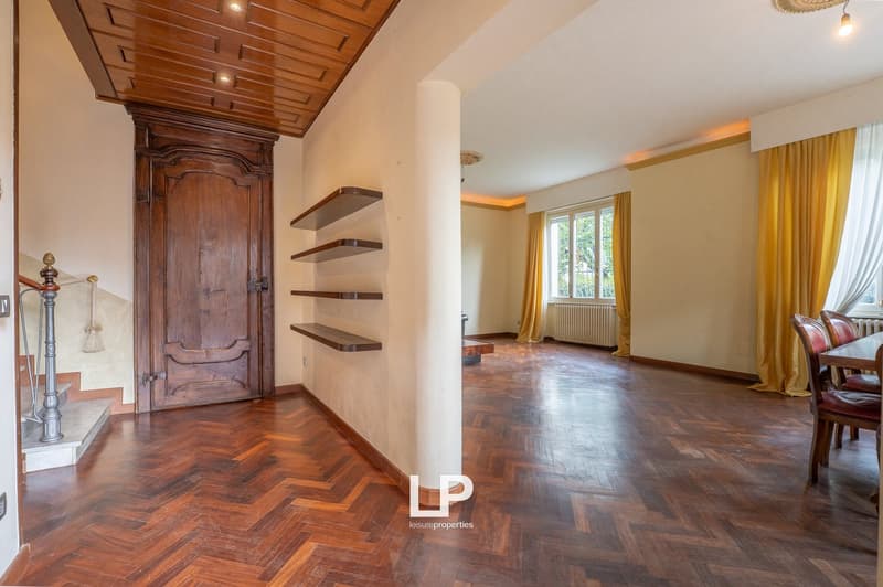 wooden floor, wooden door, shelves, radiator, windows with curtains, dining table and chairs