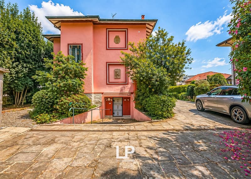 pink house, red roof, red door, car parked in front, stone driveway, trees and bushes