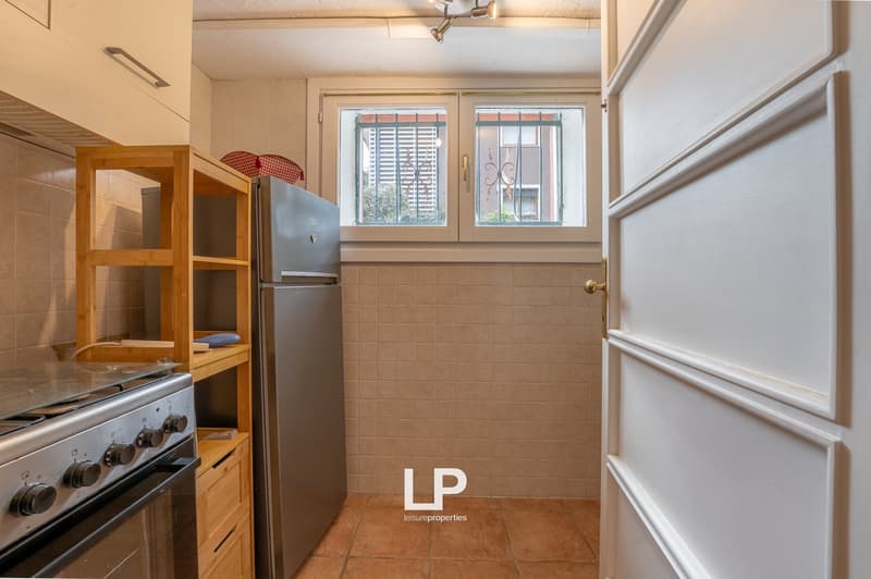 kitchen with stove, refrigerator, wooden shelves, tiled floor, window with grills