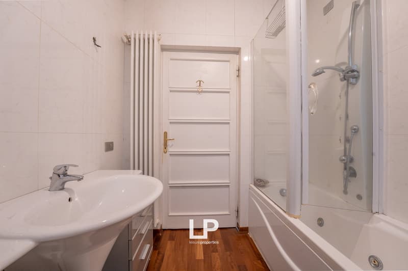 white tiles, white sink, white bathtub, glass shower enclosure, white door