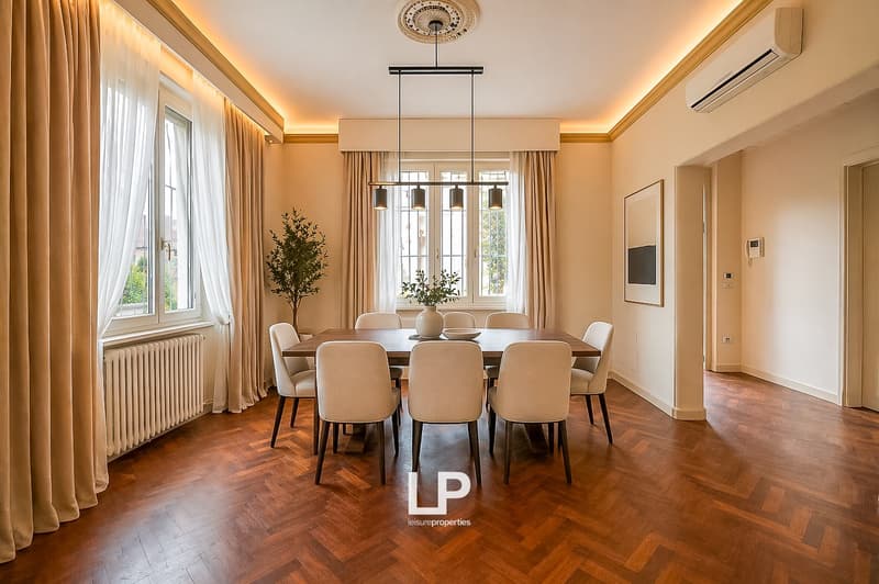 Dining room with wooden floor, large windows, dining table, chairs, pendant lights, radiator, picture frame, potted plant