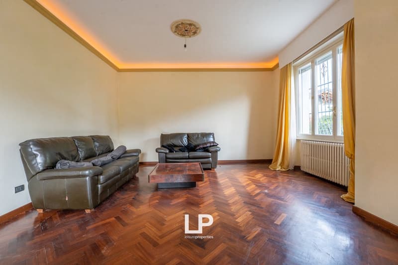 wooden floor, two leather sofas, coffee table, radiator, window with curtains