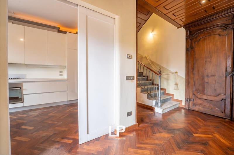 modern kitchen with white cabinets, wooden floor, staircase, wooden door