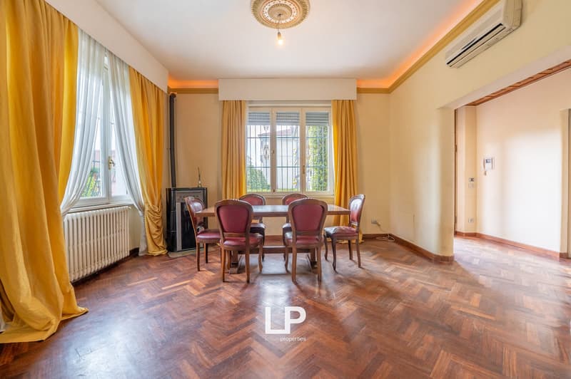 Dining room with wooden floor, dining table, chairs, radiator, windows with curtains, air conditioner