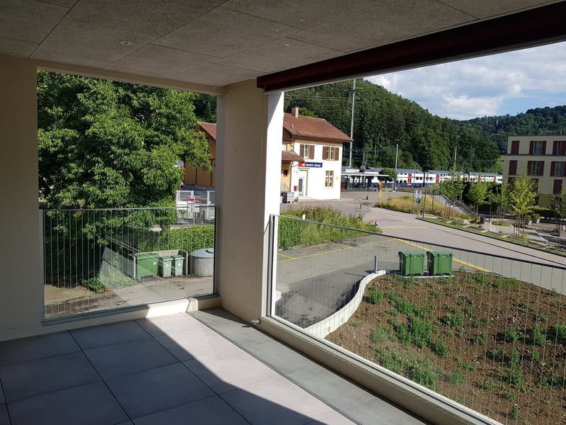 Heller Wohnbereich mit großflächiger Verglasung und Zugang zu Balkon mit Ausblick