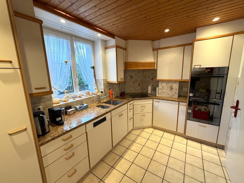 modern kitchen with granite countertops, white cabinets, double oven, dishwasher, coffee machine, sink, window with curtains