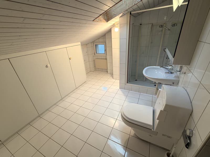 Bathroom with white tiles, white toilet, white sink, glass shower enclosure, white cabinets, small window