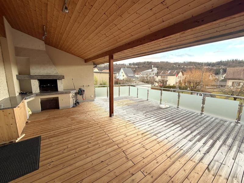 wooden deck, fireplace, glass railing, black rug, countertop, view of the town