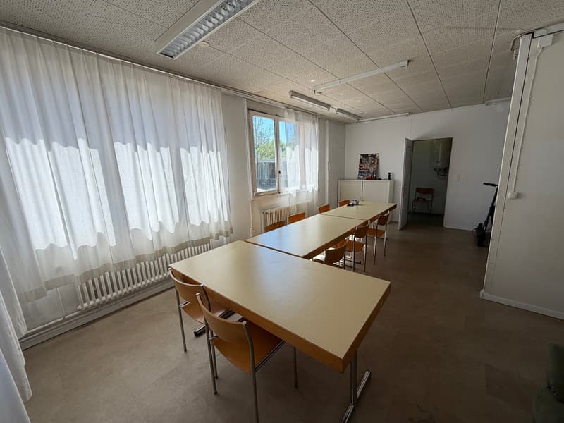 empty room with long tables, chairs, white curtains, radiators, ceiling lights