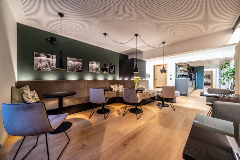 Dining area with modern seating arrangement, wooden floors, hanging lamps, and a decorative wall with photos