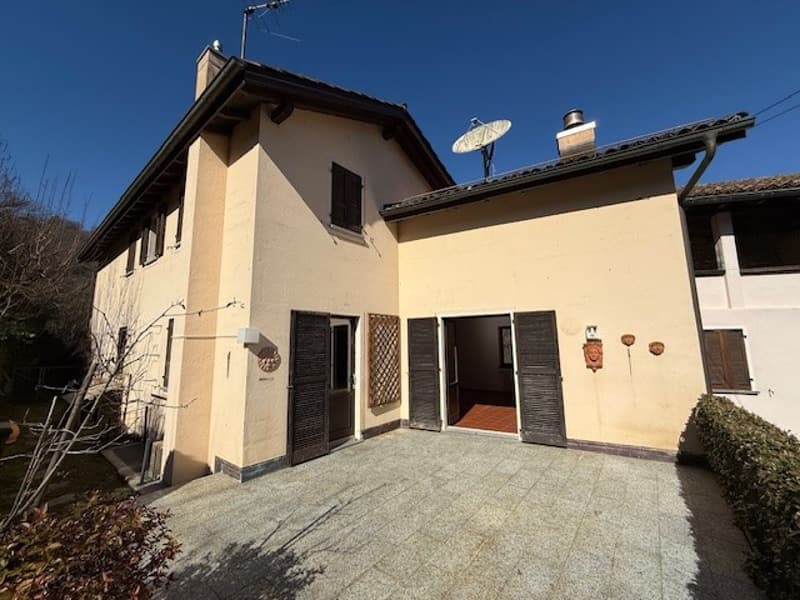 Two story house, beige exterior, brick chimney, garage, two satellite dishes, black doors