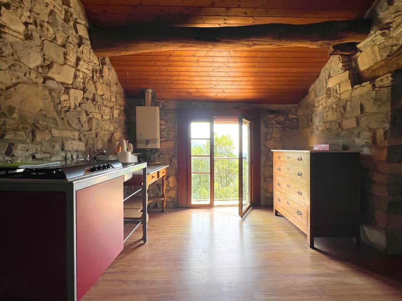 kitchen with a small window, stone walls, wooden counter, sink, and a wooden cabinet