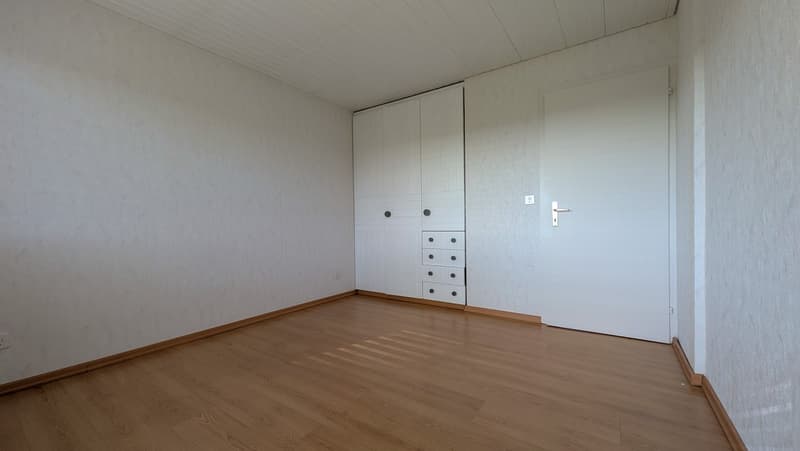 empty room, wooden floor, white walls, white wardrobe, drawers, door