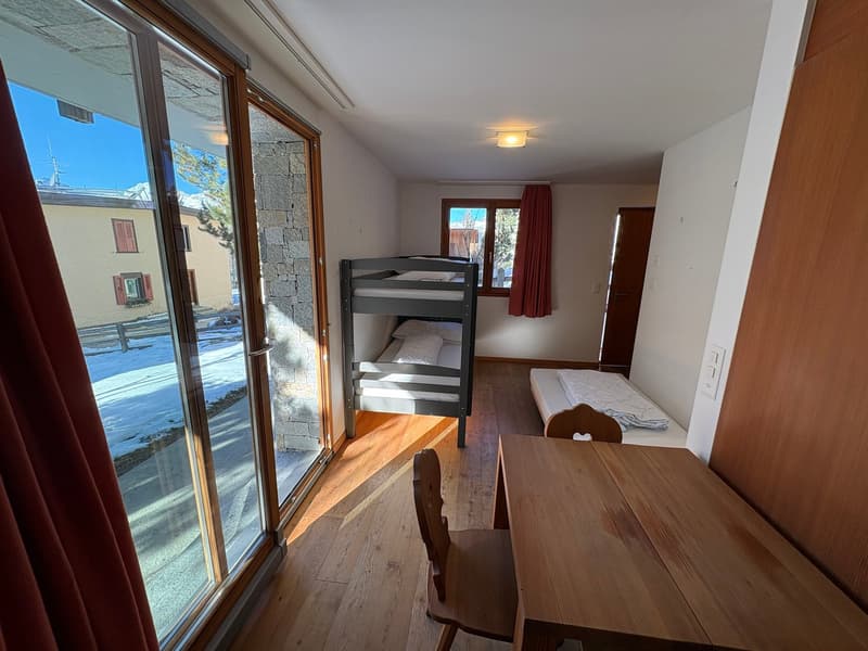 single room with bunk beds, desk, and wooden chair