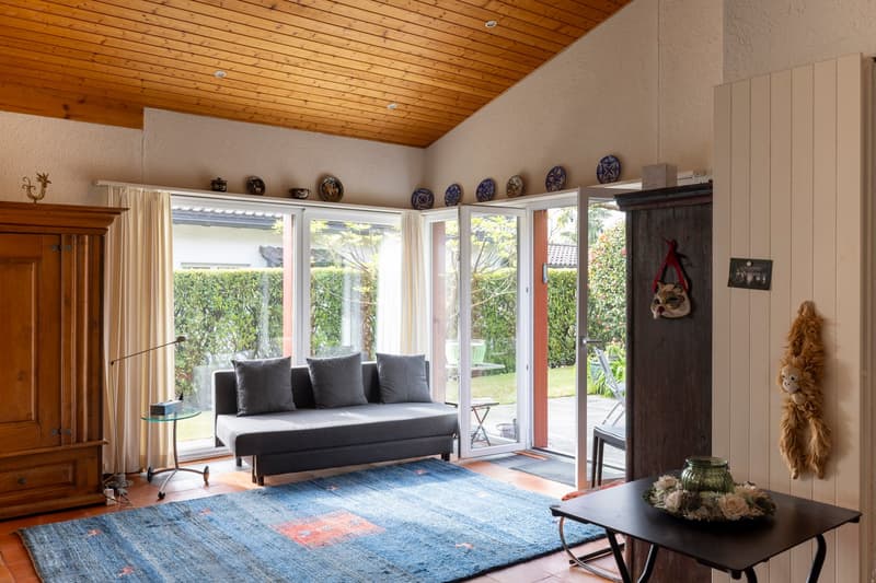 wooden ceiling, gray sofa, blue rug, glass table, sliding glass doors, balcony