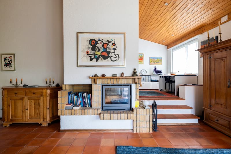 Fireplace, wooden ceiling, wooden floor, wooden furniture, paintings, books, candles, clock, window