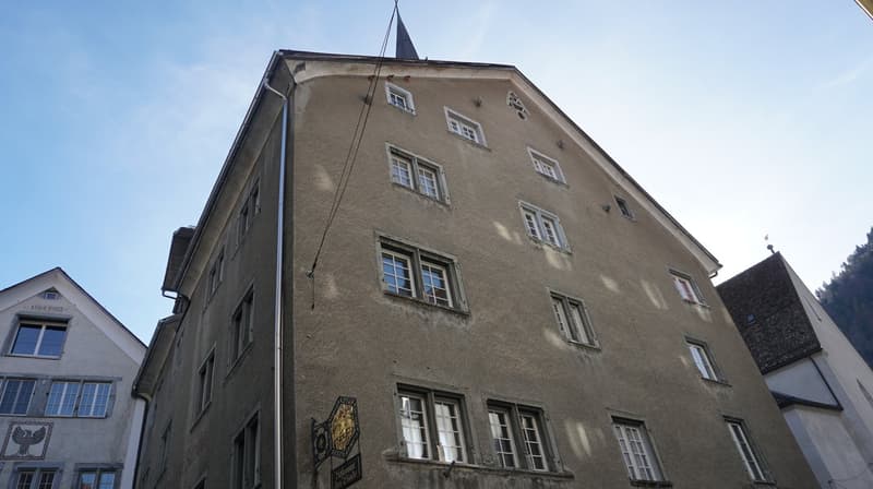 Old building with multiple windows, steeple, and a sign on the front