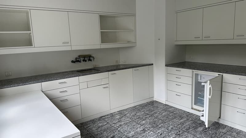Spacious kitchen with white cabinets, granite countertops, and built-in appliances including a dishwasher.