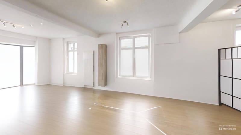 Spacious, bright living room with large windows, hardwood floors, and a built-in storage cabinet.