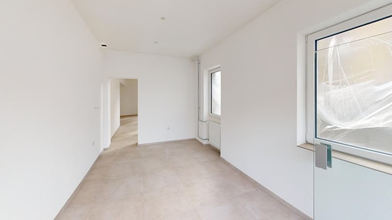 an empty hallway with white walls, tile floor, white doors, glass windows