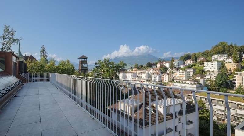 Balcony with tiled floor, metal railing, view of the city and mountains