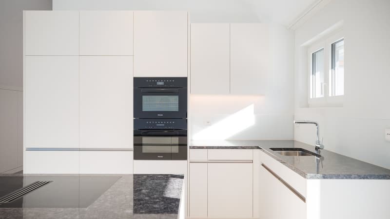 modern kitchen with white cabinets, granite countertops, double oven, sink, faucet, window