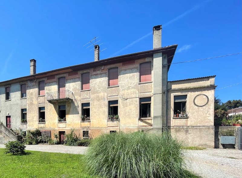 Old building, multiple windows, balcony, multiple chimneys, garden, gravel driveway