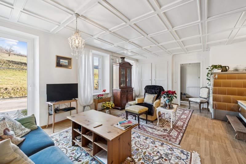 Traditioneller Charme - heimeliger Wohnbereich mit praktischem Einbauschrank und klassischem Kachelofen im EG
