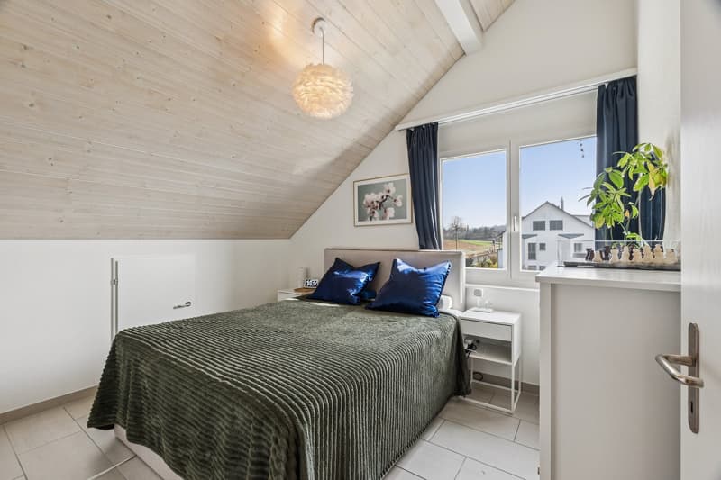 Helles Schlafzimmer mit grossem Fenster und charmanten Dachschrägen und zusätzlichem grosszügigen Stauraum