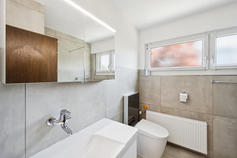 Das modernisierte Badezimmer bietet ein Tageslichtfenster sowie eine komfortable, begehbare Dusche.