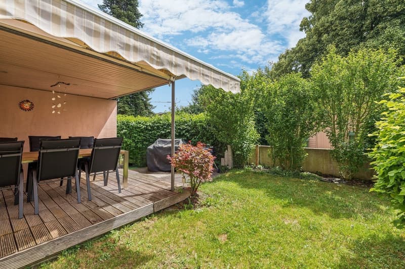 Der überdachte Sitzplatz lädt zum Verweilen im pflegeleichten Garten ein.