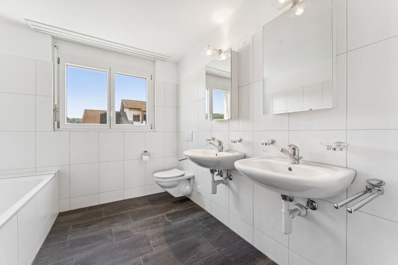 Das En-suite-Badezimmer im Hauptschlafzimmer überzeugt mit einem Doppel-Lavabo, einer Dusche sowie einer Badewanne und bietet höchsten Komfort im Alltag