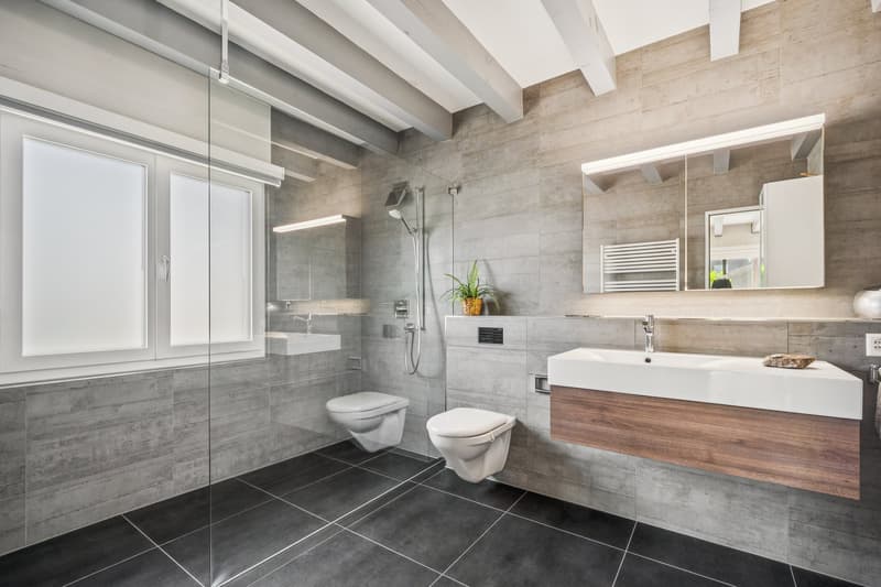 Das Badezimmer im Erdgeschoss überzeugt mit Badewanne, Dusche und Doppel-Lavabo und lässt keine Wünsche offen