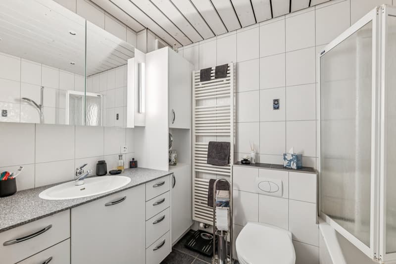 Modernes Badezimmer mit Badewanne inklusive Duschmöglichkeit, praktischen Einbauschränken und zeitloser Ausstattung