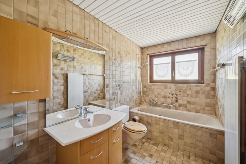 Das helle Badezimmer mit natürlichem Tageslicht, einer Badewanne und viel Platz für den täglichen Komfort