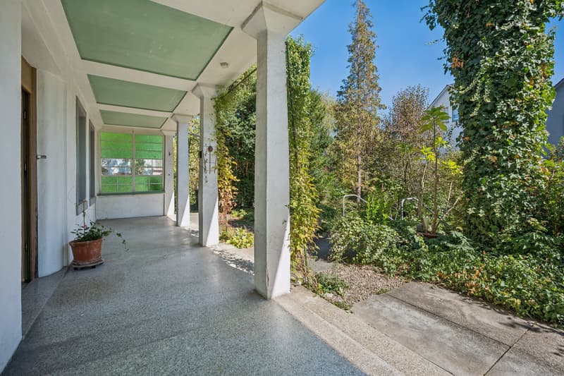 Grosszügige Veranda mit Blick ins Grün und geschütztem Aufenthaltsbereich im Freien.